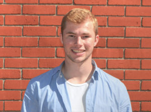 Ben Scholte smiling in front of a brick wall.