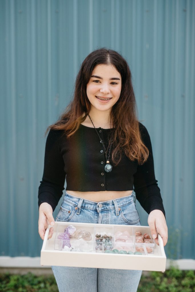 A young woman participating in Summer Company, a youth entrepreneur program, holding a box of crystals.