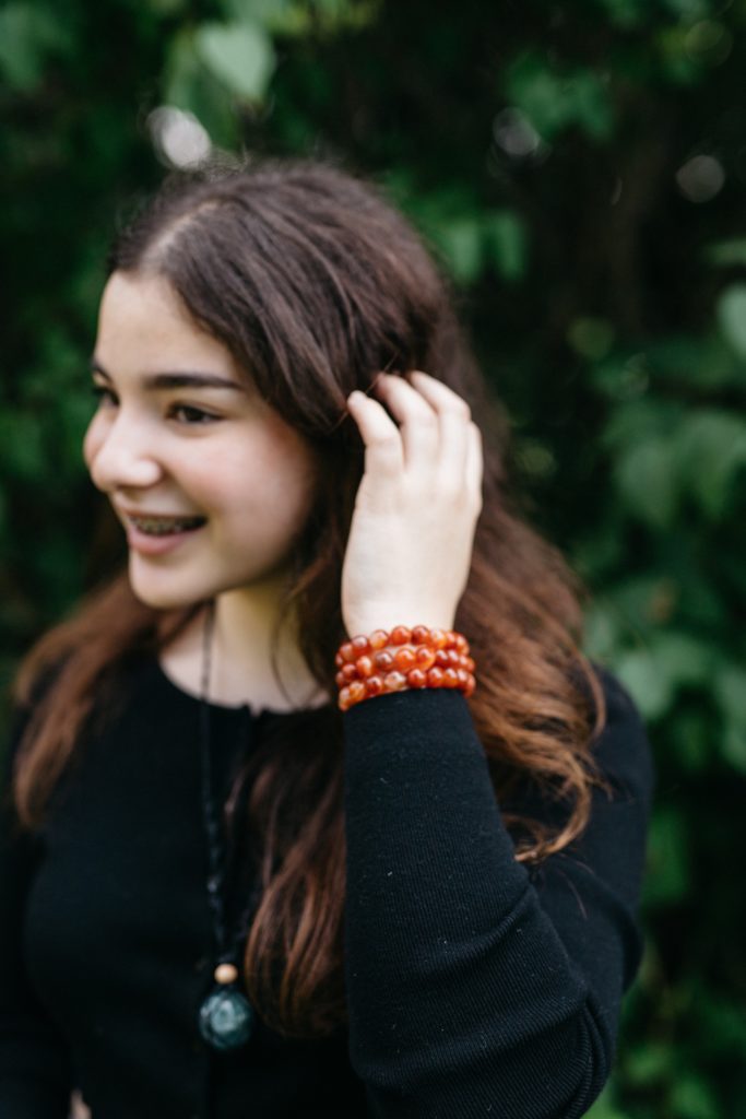 A woman wearing a black shirt and orange bracelets.