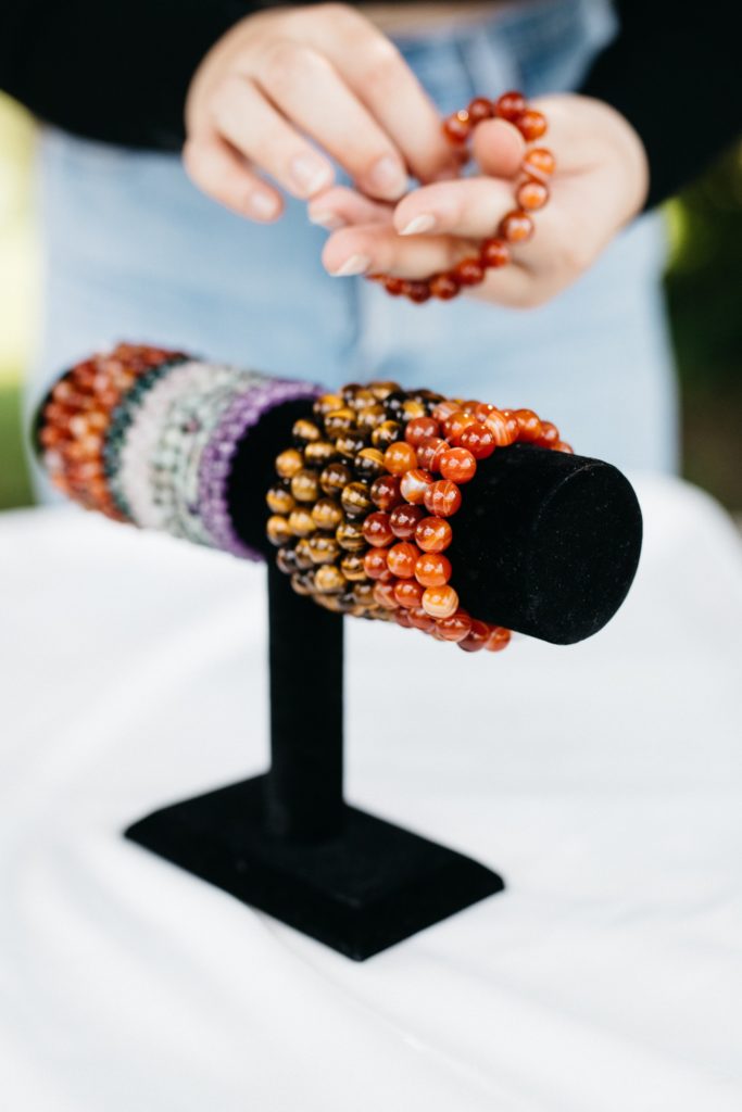 A woman is putting bracelets on a stand.