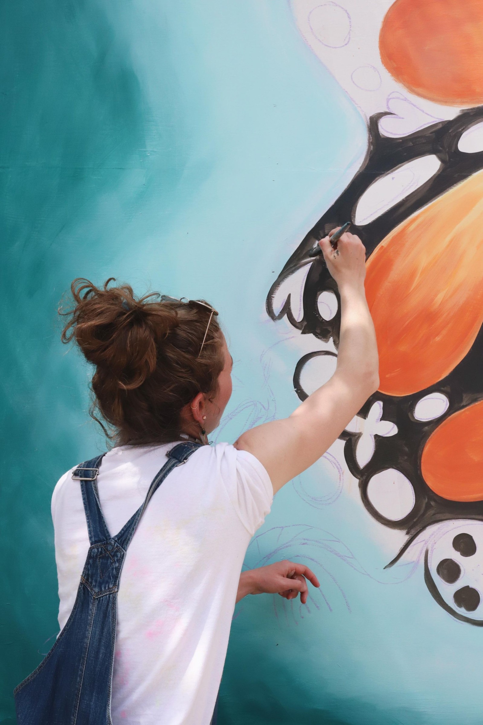 A woman from a starter company painting a butterfly on a wall.